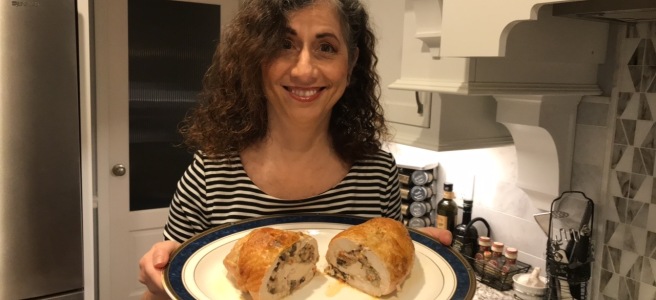 Kathryn holding a platter with a turkey roll that has been cut in half and the swirl of sausage and mushroom ragù filling visible.